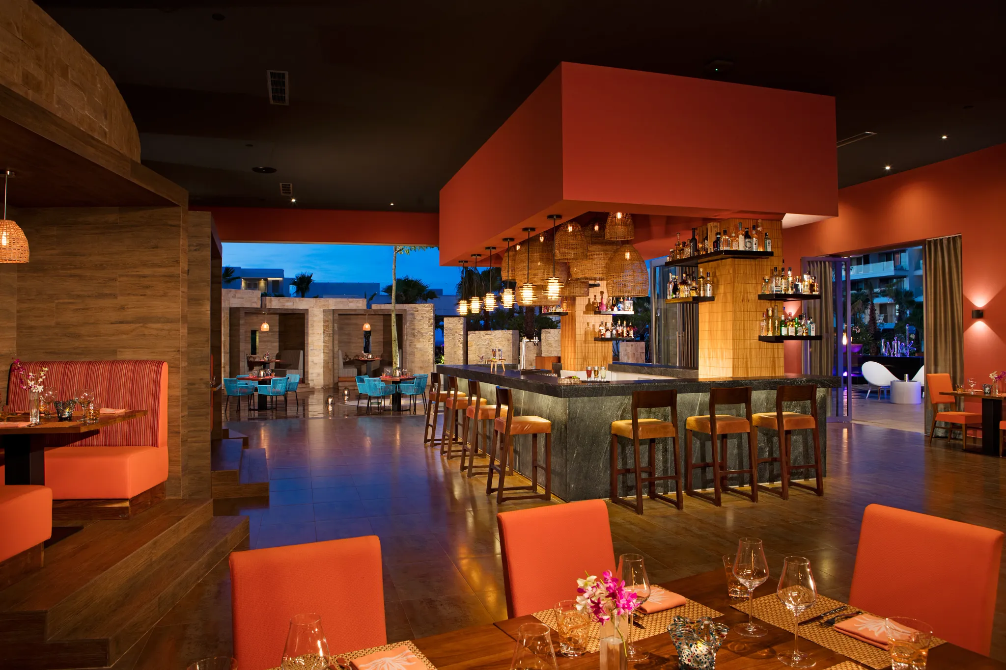 Warm, colorful interior of Picante, the Mexican restaurant at Breathless Riviera Cancun, featuring bar seating and woven lights.
