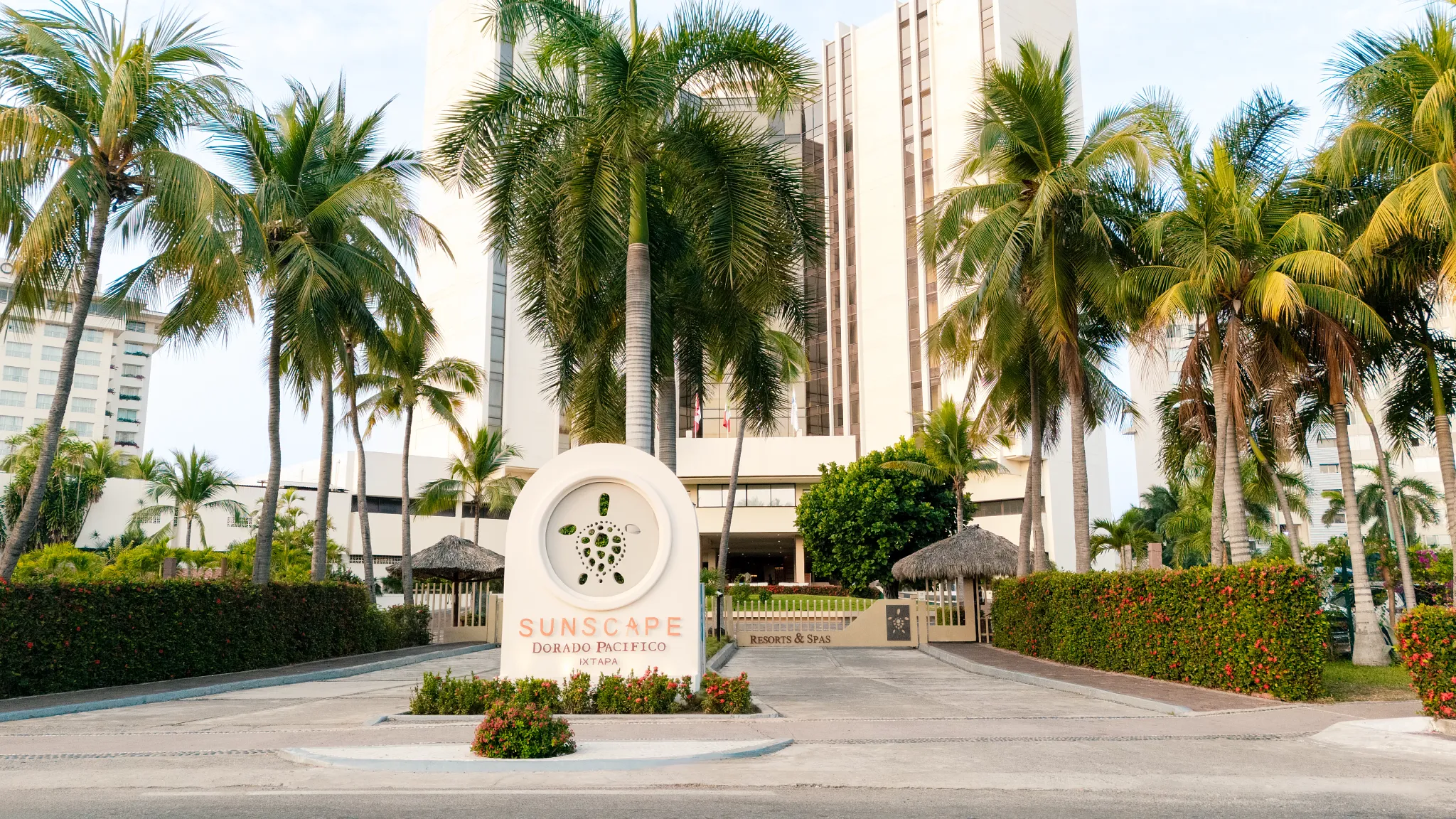 Main entrance and motor lobby of Sunscape Dorado Pacifico Ixtapa surrounded by palm trees and tropical landscaping.