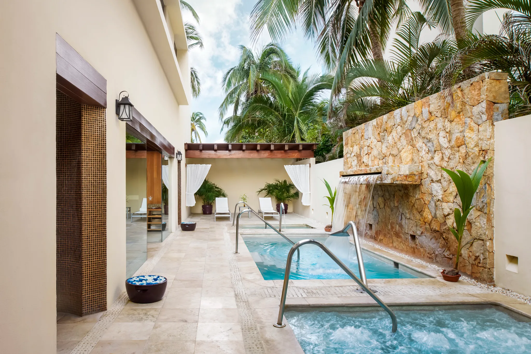 Outdoor hydrotherapy pool with waterfall feature at Sunscape Dorado Pacifico Ixtapa spa.