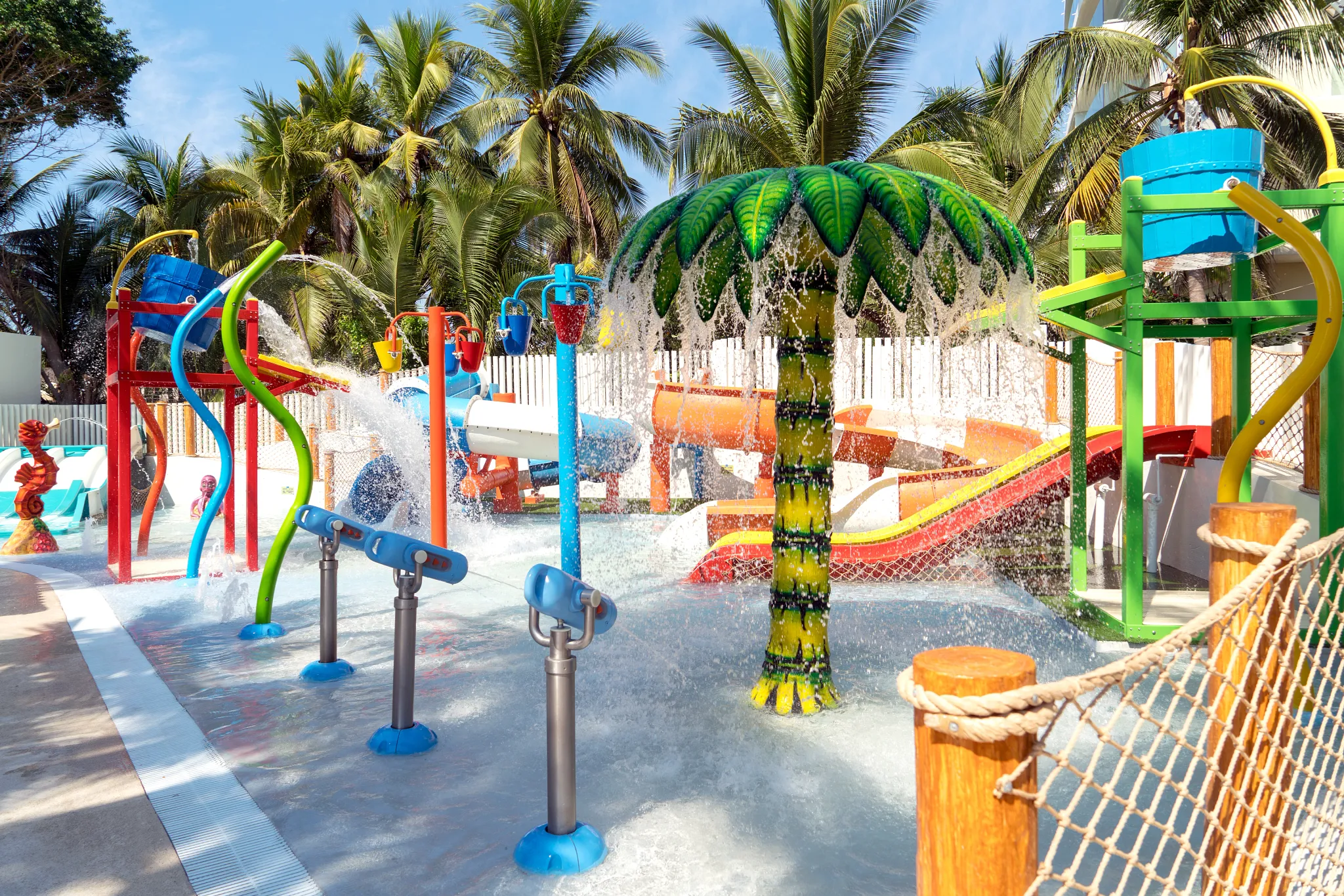Kids splash area with palm tree water feature and slides at Sunscape Dorado Pacifico Ixtapa Sunny Splash Park.