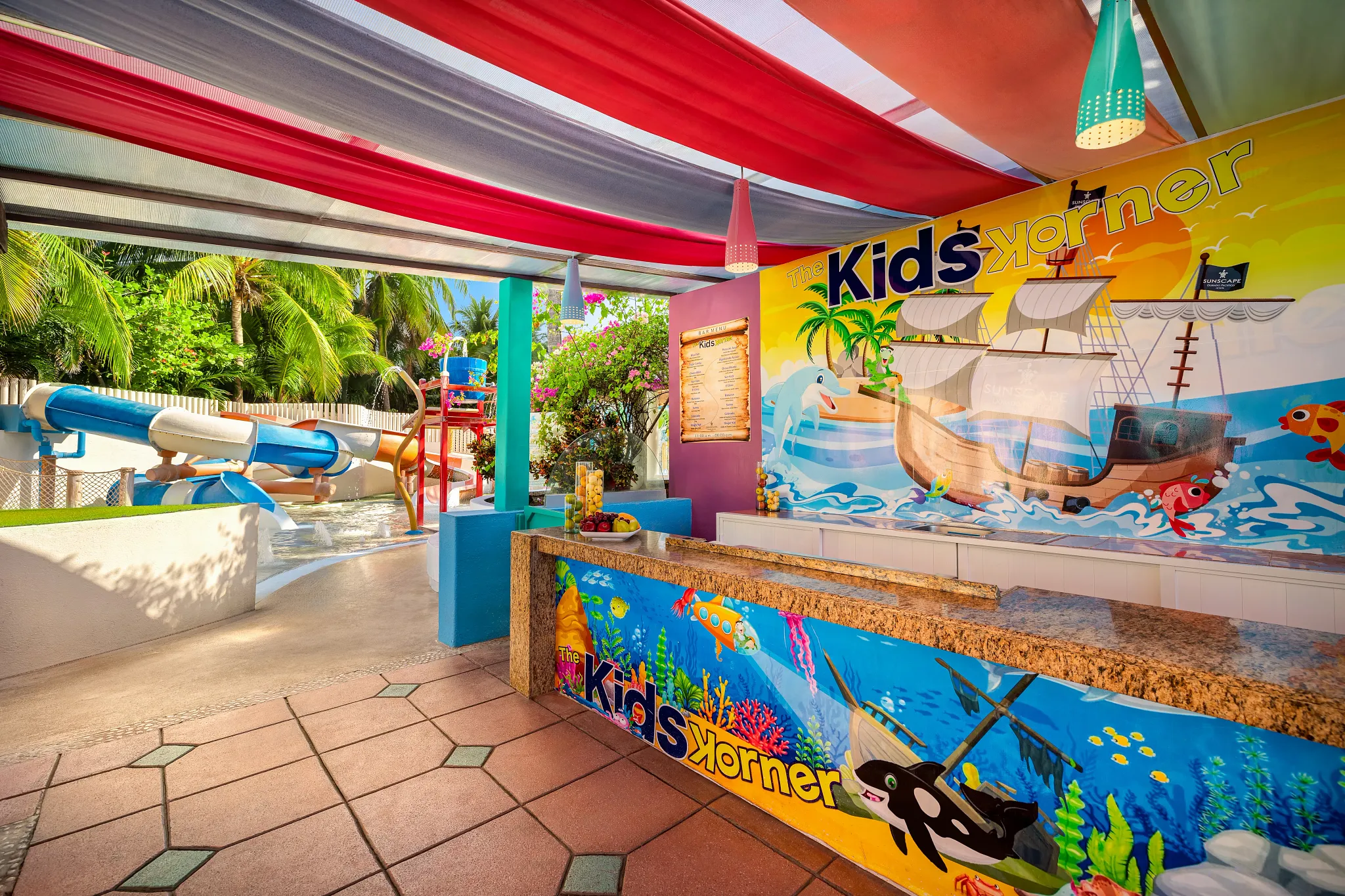 The Kids Korner bar at Sunscape Dorado Pacifico Ixtapa featuring colorful ocean-themed décor, kids drink station, and nearby water slides.