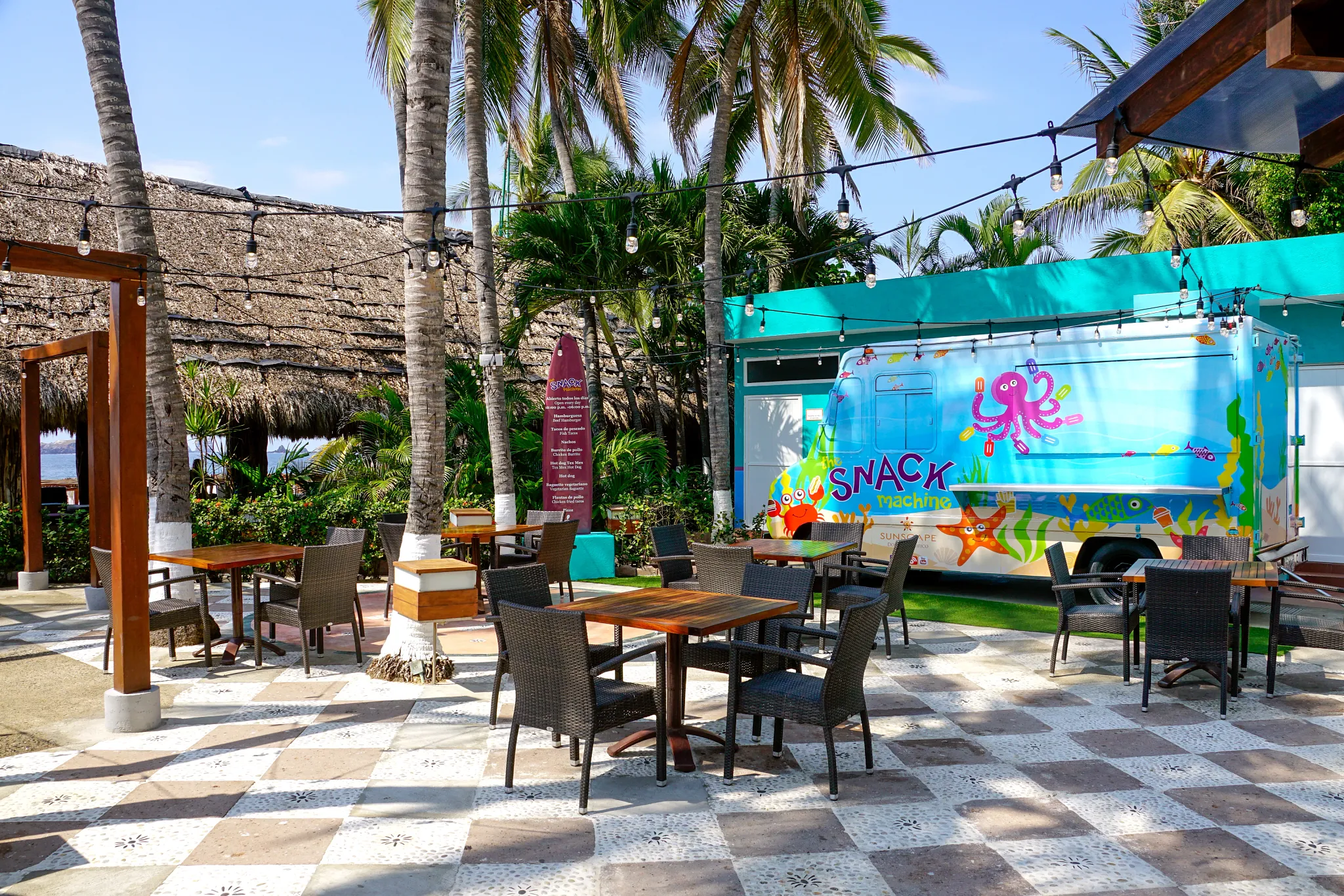 The Snack Machine food truck at Sunscape Dorado Pacifico Ixtapa featuring colorful ocean-themed design, outdoor seating, and tropical palm surroundings.